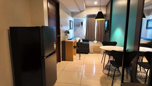 Une chambre d’hôtel moderne dotée d’un coin cuisine, d’une table à manger avec des chaises, d’un canapé et d’une télévision.