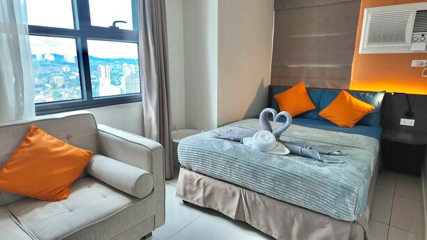 Une chambre d’hôtel équipée d’un lit, d’un canapé, d’une fenêtre donnant sur la ville et d’un appareil de climatisation.