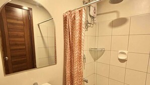 Une salle de bain équipée d’un lavabo, d’un miroir, d’une douche et de toilettes.