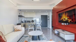 A modern living room with a sofa, a round table, and a TV mounted on a red wall.
