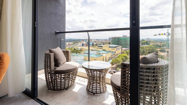A balcony with wicker furniture, a glass door, and a city view.