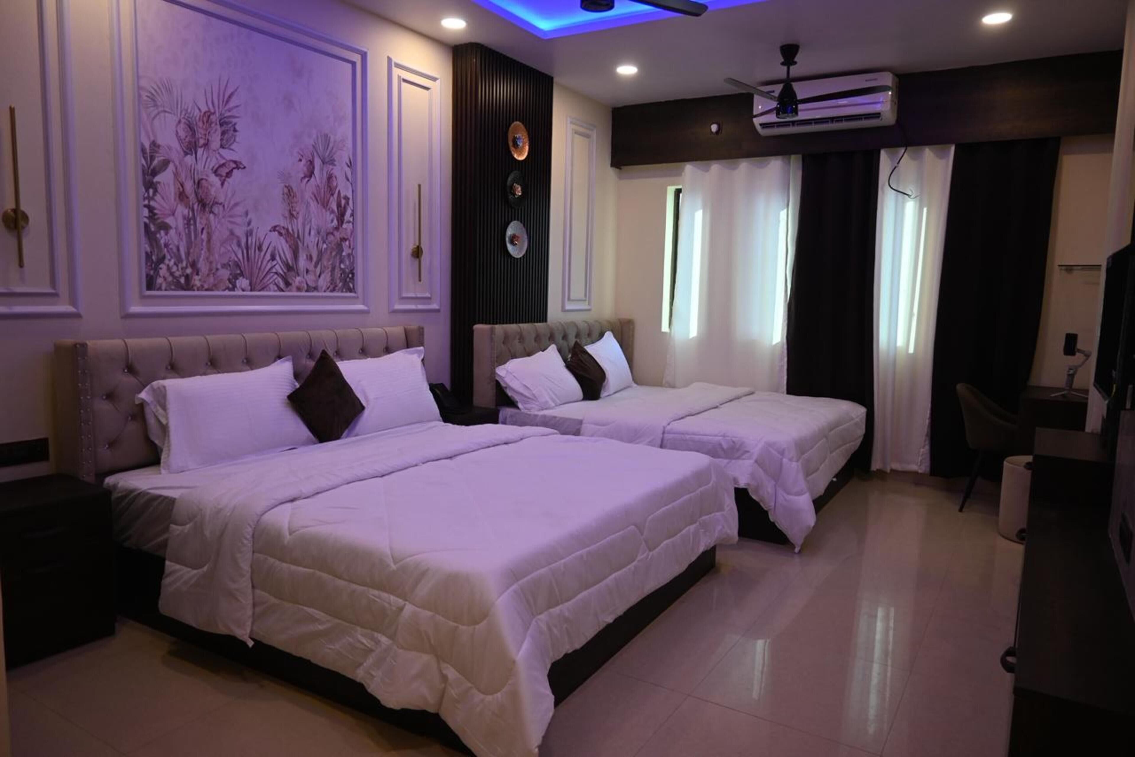 Une chambre d’hôtel avec deux lits, un ventilateur de plafond, un appareil de climatisation, un tableau au mur et un bureau avec une chaise.