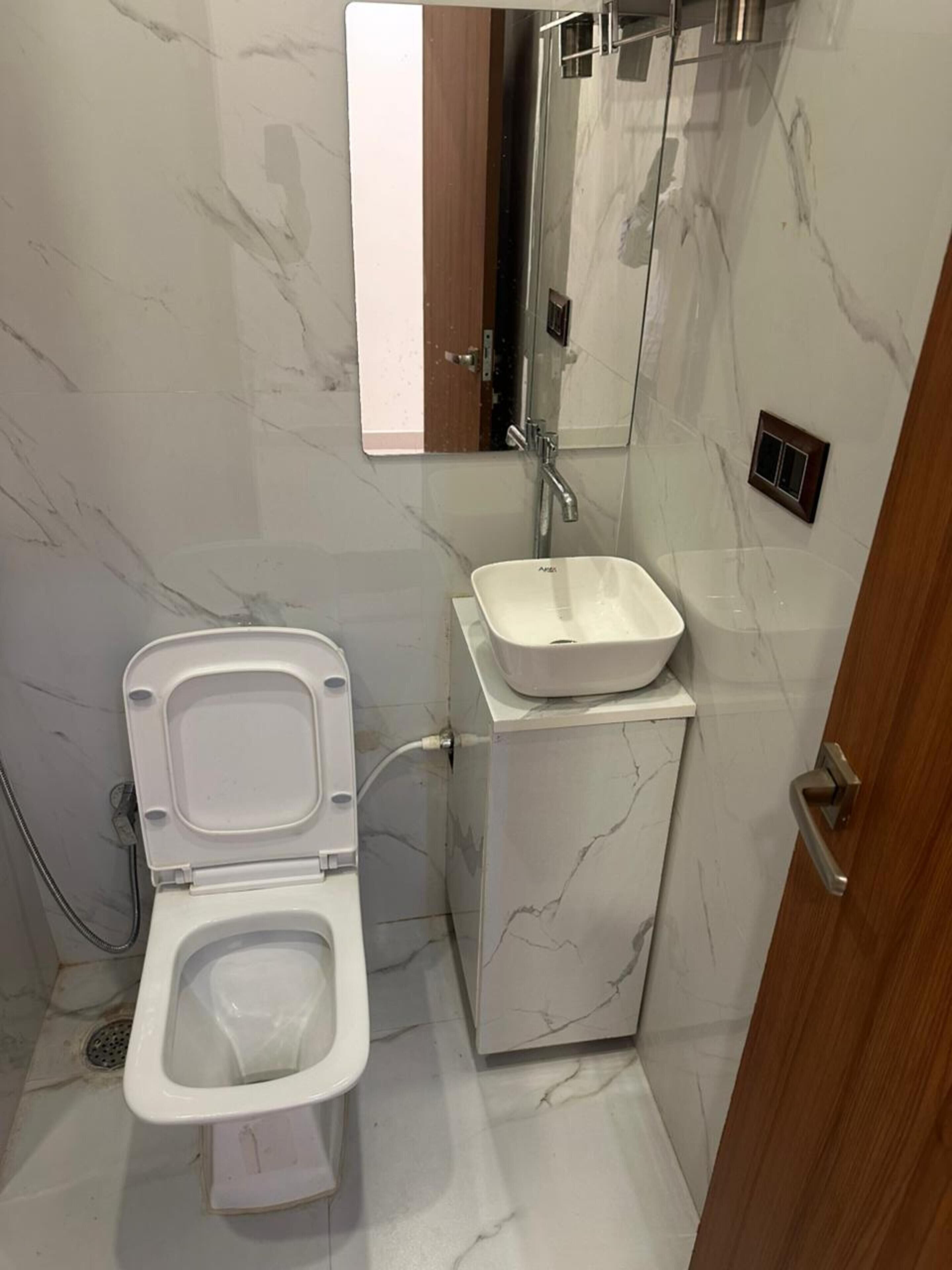 A bathroom with a toilet, a sink, and a mirror.