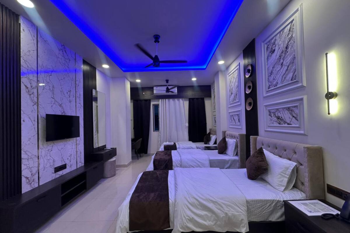 A modern hotel room with two beds, a flat-screen TV, ceiling fan, and marble wall decor.