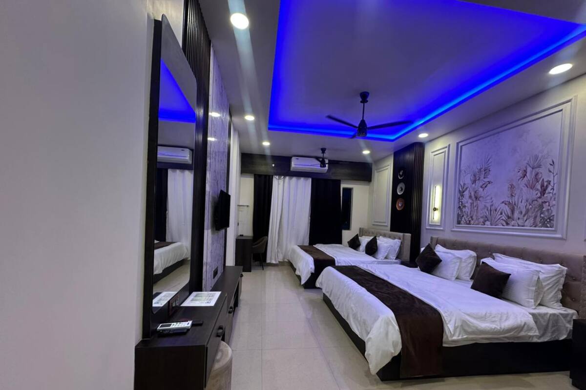 A hotel room with a bed, bedside tables, a desk, a chair, a ceiling fan, and a large mirror.