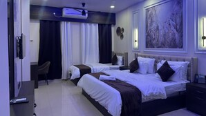 Habitación de hotel con dos camas, un escritorio, una silla y un ventilador de techo.