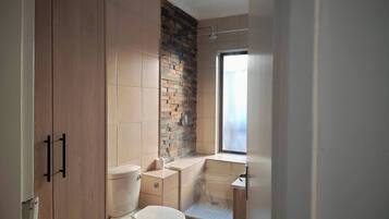 A bathroom with a toilet, a shower, and a window.