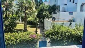 Un quartiere residenziale con edifici bianchi, un giardino con palme e un cancello blu.