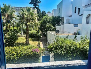A residential area with white buildings, a garden with palm trees, and a blue gate. - Dar Nino Cozy 2 Bedroom Apartment in La Marsa Plage (La Marsa)