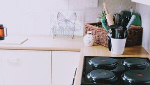 Une cuisine équipée d’une cuisinière, d’une machine à café, d’un panier rempli d’ustensiles de cuisine et d’un tableau encadré posé sur le comptoir.