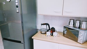 Une cuisine équipée d’un réfrigérateur en acier inoxydable, d’une machine à café, de deux tasses et d’un grille-pain.