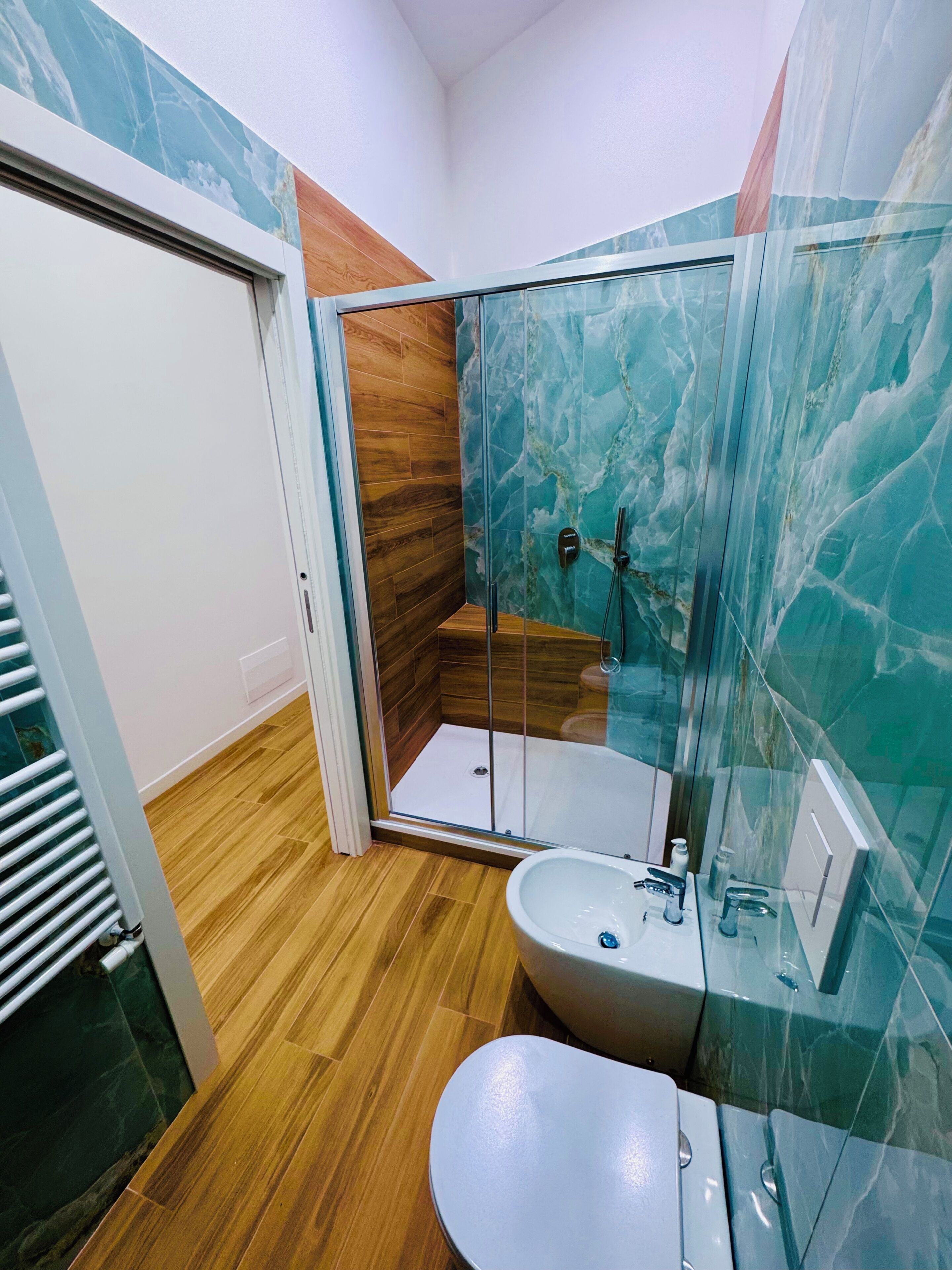 Un bagno con cabina doccia in vetro, lavabo e water.