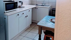 A kitchen with white cabinets, a microwave, a sink, and a table with a placemat.
