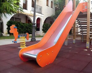 Un parque infantil con un tobogán y un columpio con forma de caballo.