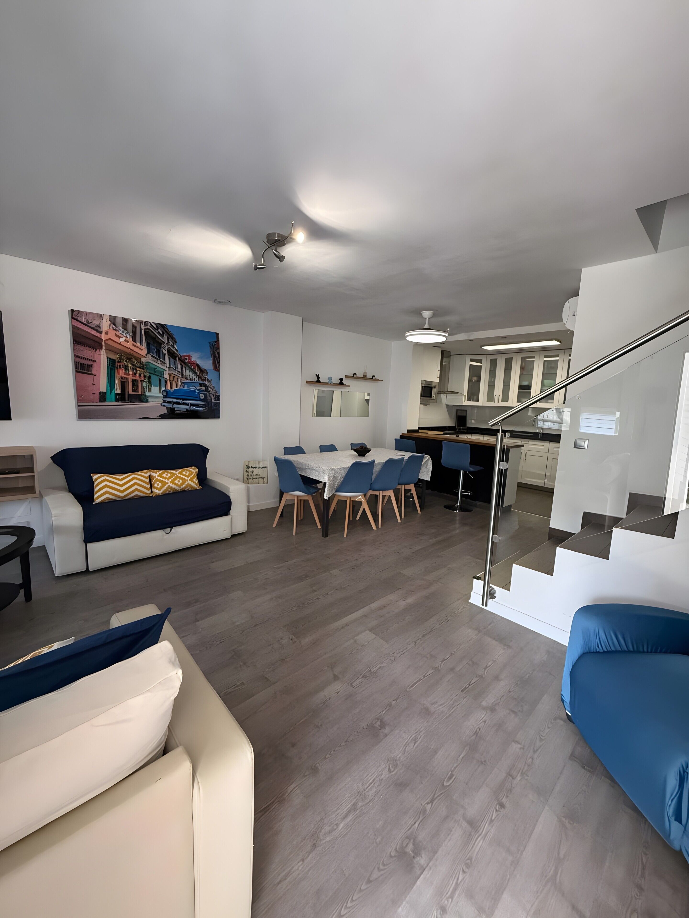 Una sala de estar moderna con un sofá, una mesa de comedor y una cocina al fondo.