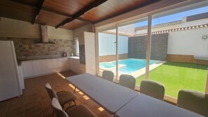 A kitchen with a tiled backsplash and a dining area with a table and chairs.