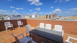 A rooftop terrace with a table and chairs, a brick wall, and a cityscape view. - Country House 'Villam Rodericus Nicolaus' with Private Pool, Wi-Fi and Air Conditioning (Lantejuela)