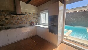 A kitchen with a tiled backsplash, a window, and an outdoor pool view. - Country House 'Villam Rodericus Nicolaus' with Private Pool, Wi-Fi and Air Conditioning (Lantejuela)