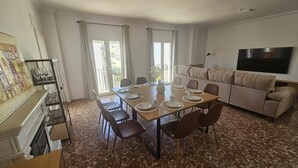 A dining area with a table set for four, a sofa, a TV, and a kitchen area with a dishwasher. - Country House 'Villam Rodericus Nicolaus' with Private Pool, Wi-Fi and Air Conditioning (Lantejuela)