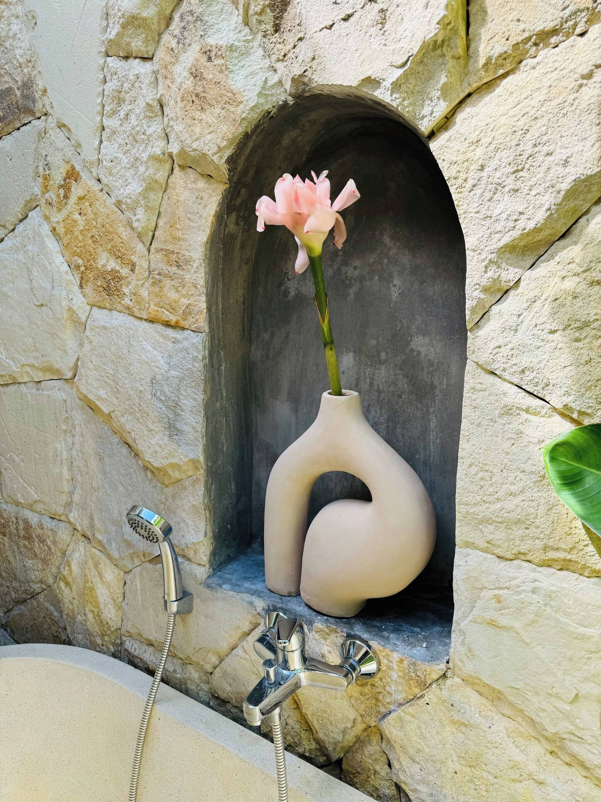 Un mur de pierre avec un vase à fleurs et une douche.
