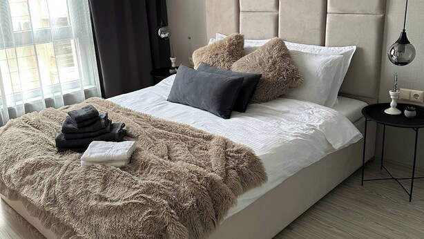Quarto moderno com cama grande, manta macia e mesa de cabeceira com abajur.
