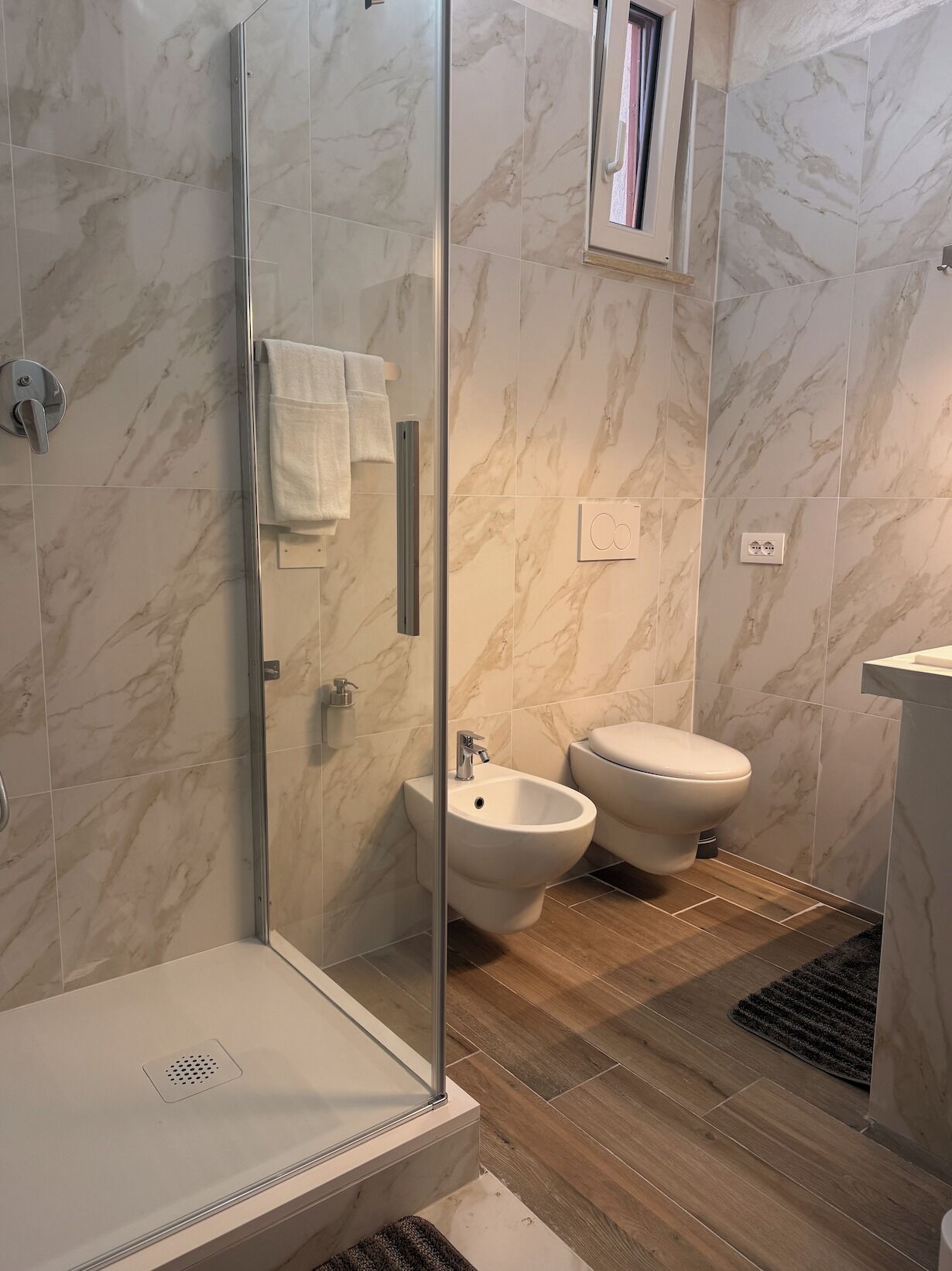 Un baño moderno con cabina de ducha de vidrio, un bidé y un inodoro.
