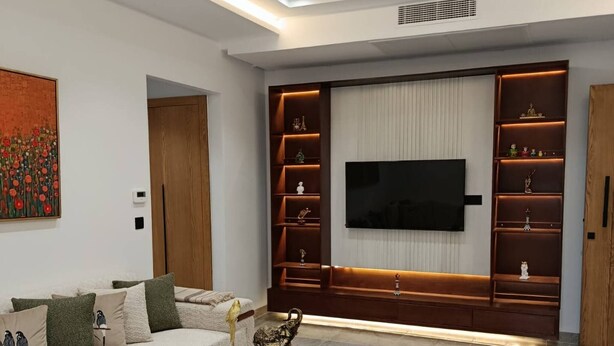 Ein modernes Wohnzimmer mit einer Couch, einem Couchtisch, einem Fernseher und eingebauten Regalen.