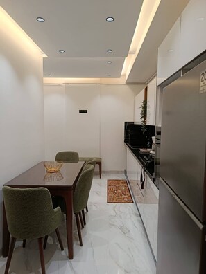 A compact kitchen with a dining area, a refrigerator, and a small island with a sink. - Charming 2-Bedroom Apartment in Tunis with City Views (Tunis)
