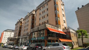 A multi-story hotel with a modern design, featuring a prominent orange awning and a sign that reads 'HOTEL BRIOS.'