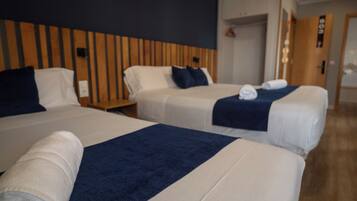 Ein Hotelzimmer mit drei Betten, einem Holzkopfteil und Holzboden.