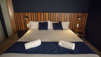 Ein Hotelzimmer mit einem großen Bett, einem Holz-Kopfteil, zwei Nachttischen und einem Beistelltisch.