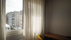 A room with a window, a radiator, a wooden table, and a yellow chair.