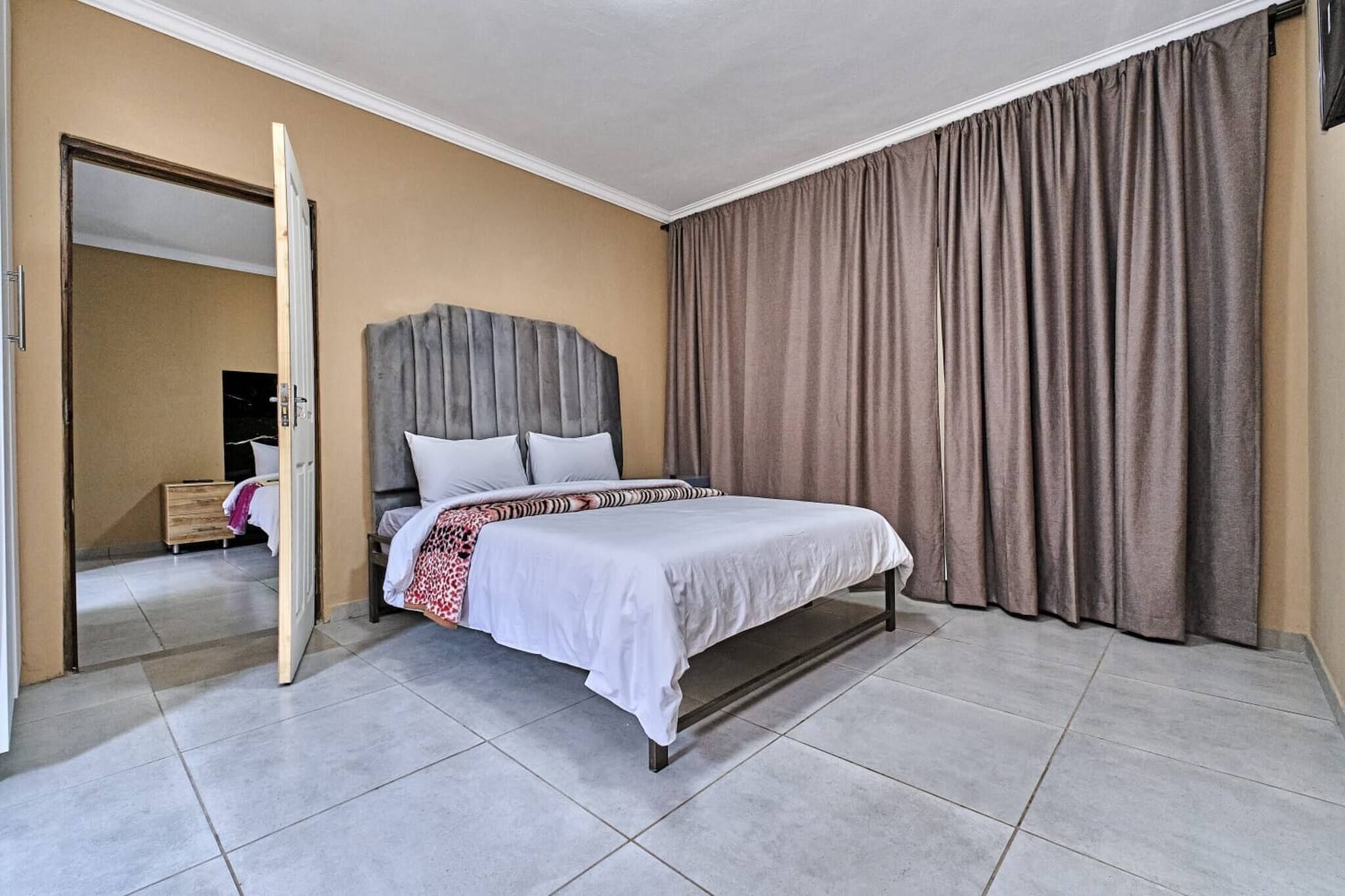 Une chambre d’hôtel comprenant un lit, une armoire, un miroir et une porte donnant sur une autre pièce.