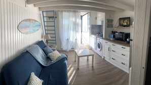 Un espace de vie compact comprenant un canapé, une table, un lave-linge et un téléviseur.