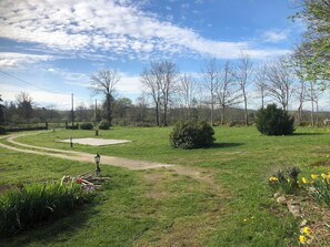 A grassy park with a paved path, a small paved area, and a few trees. - Quiet vacation home with swimming pool (Bagnols)