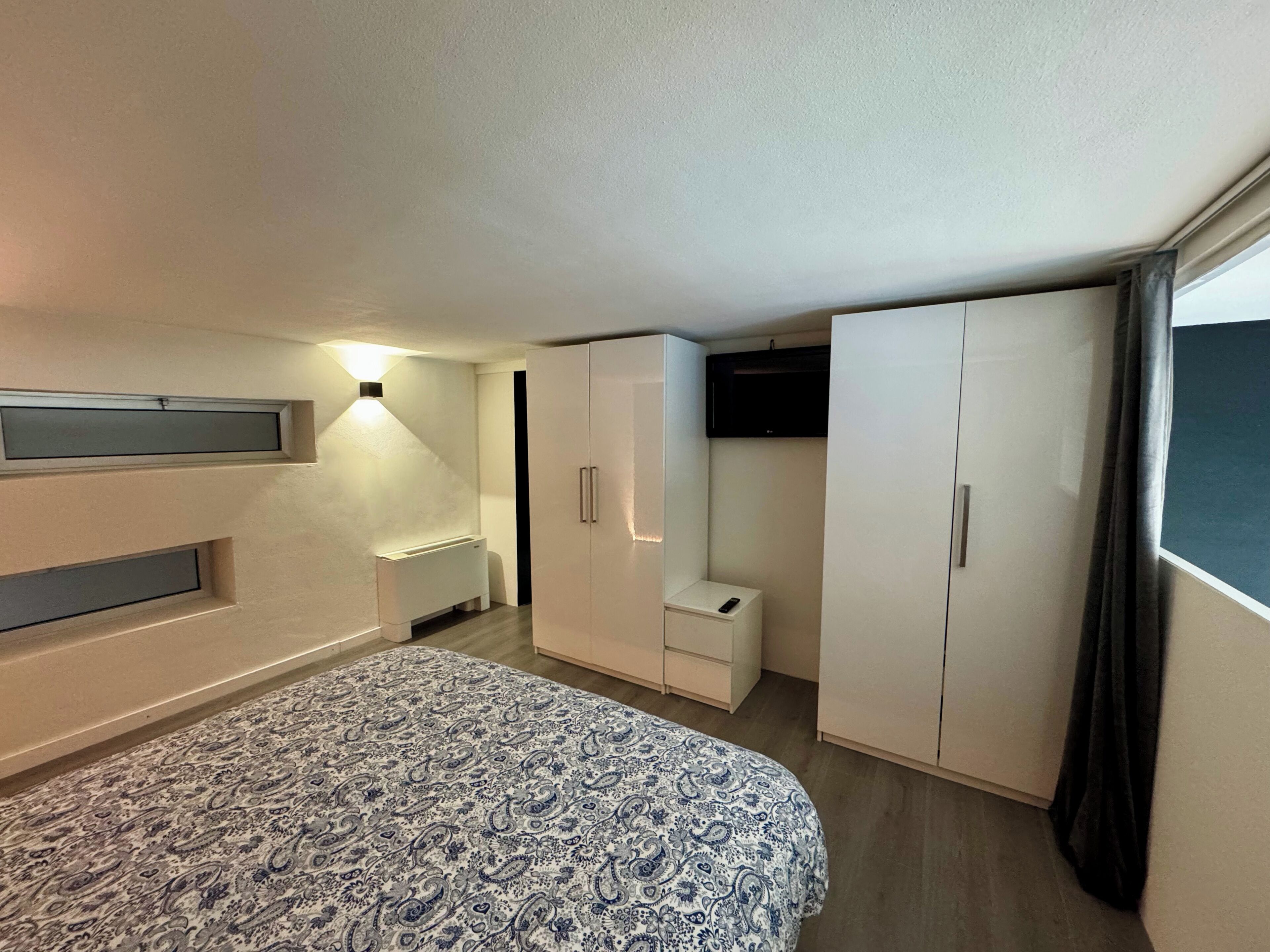Une chambre à coucher comprenant un lit, une armoire et un petit coin salon.