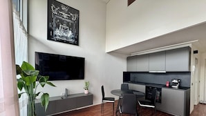 Una cocina moderna con comedor, un televisor de pantalla plana grande y una planta en maceta.