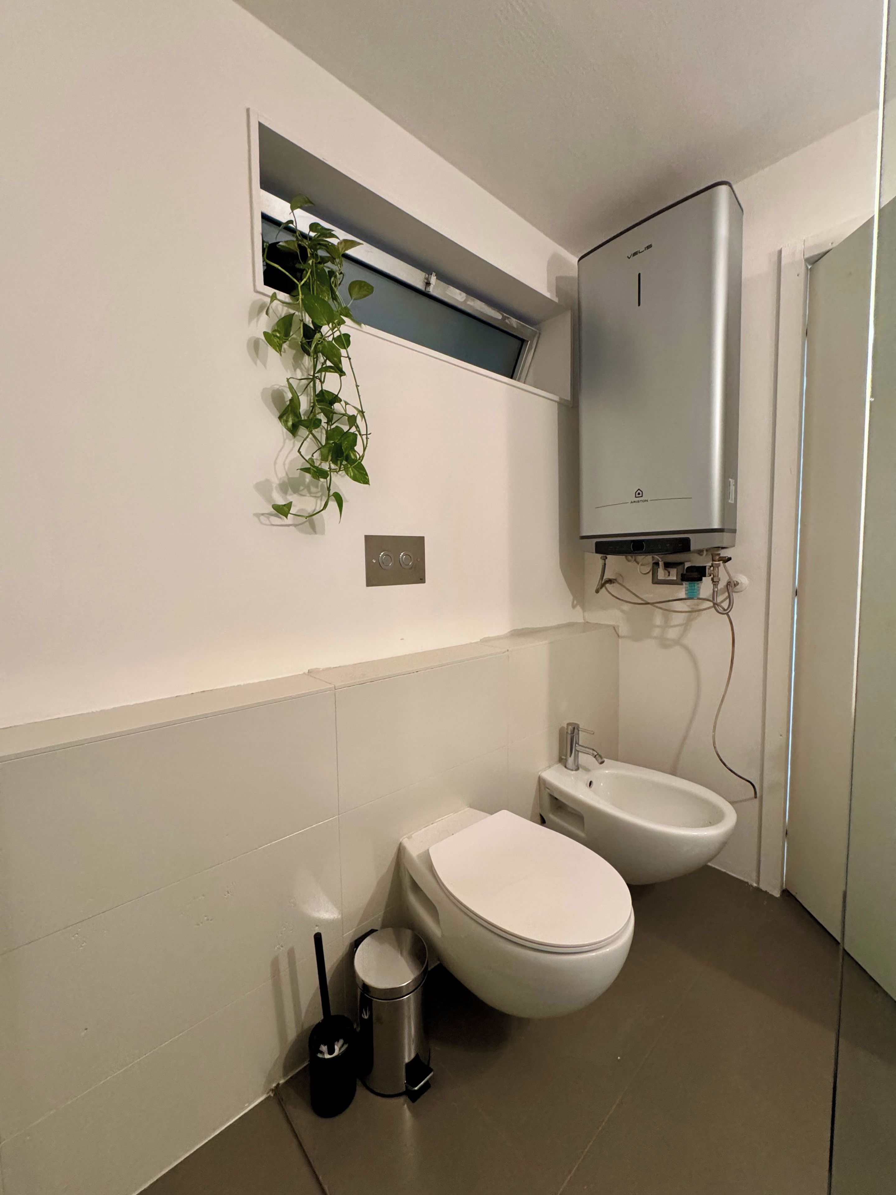 Ein Badezimmer mit Toilette, Bidet und einem wandmontierten Schrank.