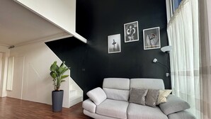 Una sala de estar moderna con un sofá gris, paredes negras y una escalera.