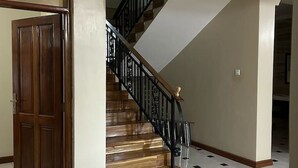 A staircase with wooden steps and black railings, leading to an upper floor.