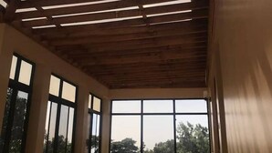An interior with a sloped ceiling, large windows, and a chair.