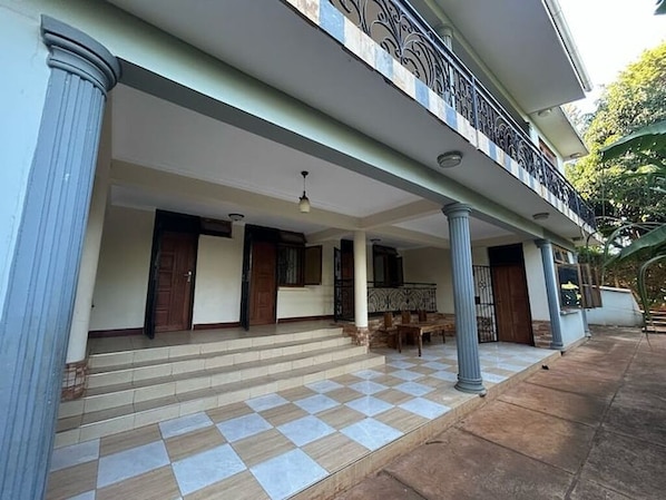 A covered outdoor area with steps leading to a door, a bench, and a railing.