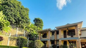 A two-story building with a paved courtyard, surrounded by greenery and a clear sky.