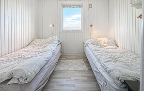 Une chambre avec deux lits simples, une fenêtre donnant sur un beau paysage et un petit tapis sur le sol.