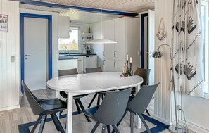 Une cuisine moderne avec des meubles blancs, une table de salle à manger ronde et quatre chaises.