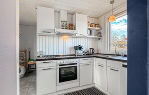 A kitchen with white cabinets, a stove, an oven, a coffee maker, and a window with a view. - 2 bedroom stunning home in Roslev (Roslev)