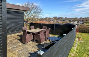 Une terrasse avec une table et des chaises, une clôture en bois et une vue sur des maisons au loin.