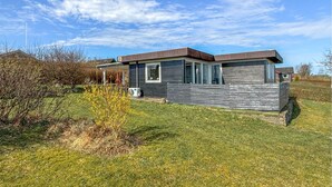 A modern single-story house with a sloped roof, large windows, and a visible garage door.