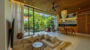 A modern living room with a large sofa, a dining area, and a kitchen. - Aricivillas (Pecatu)