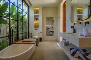 A modern bathroom with a freestanding bathtub, a large mirror, and a vanity with towels. - Aricivillas (Pecatu)